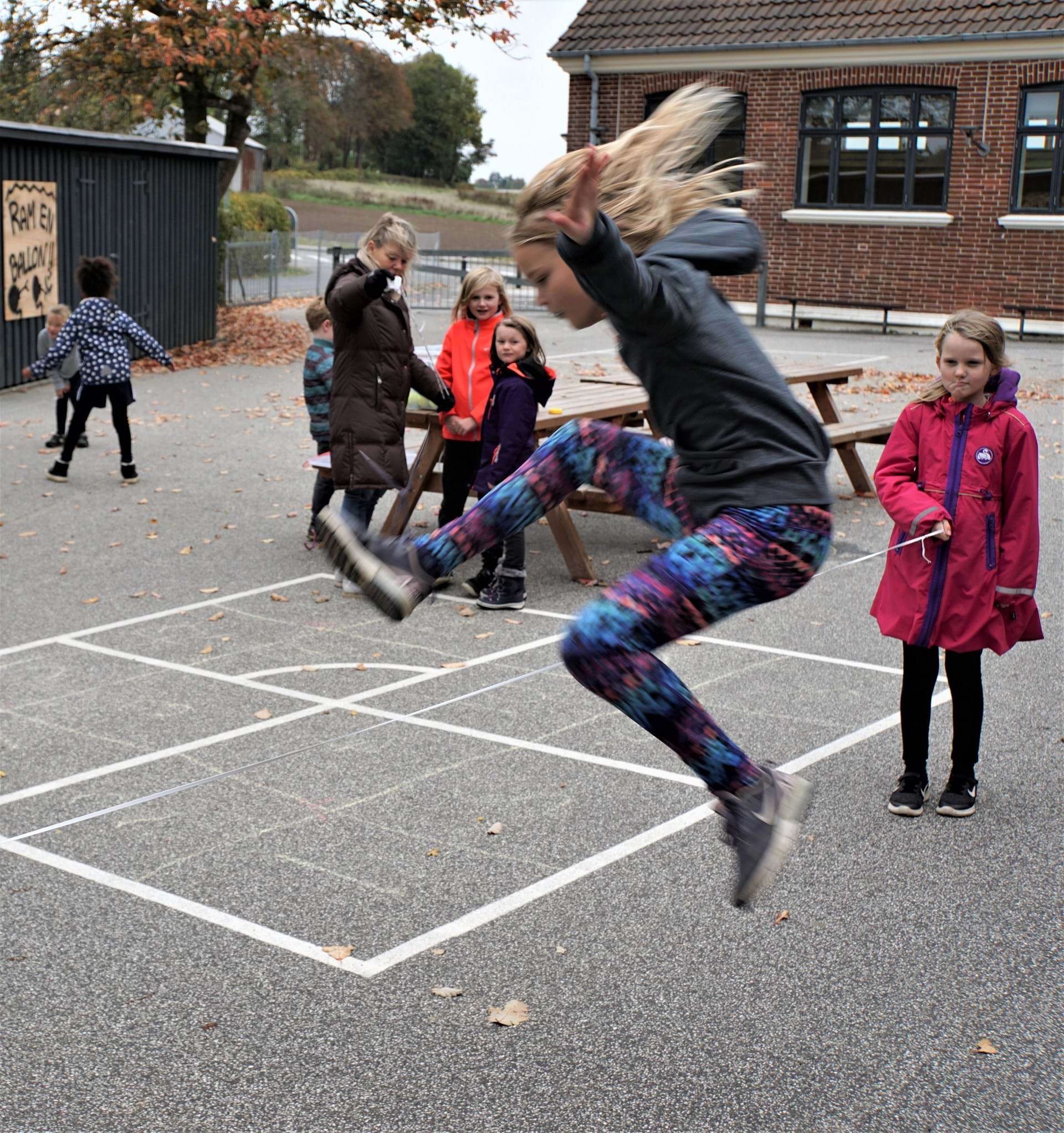 Pige i spring i skolegården